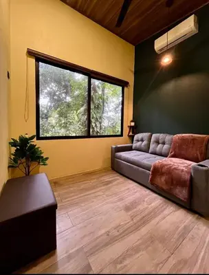 a living room with a couch and a window at Jungle House with Private Jacuzzi in Uvita