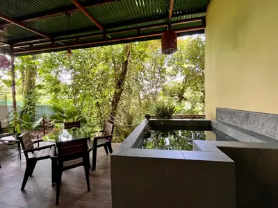 a patio with a pond and a table and chairs at Jungle House with Private Jacuzzi in Uvita