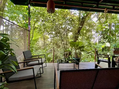 a patio with chairs and tables and trees at Jungle House with Private Jacuzzi in Uvita