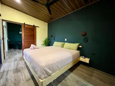 a large bed in a room with a green wall at Jungle House with Private Jacuzzi in Uvita