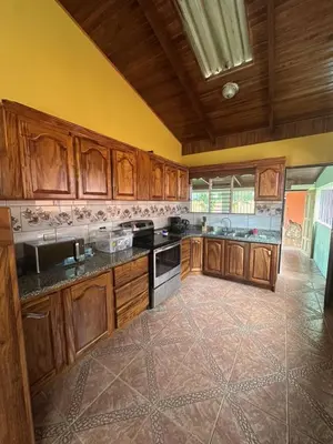 a large kitchen with wooden cabinets and a tile floor at Casa Vista al Volcan, La Fortuna in Fortuna