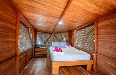a bedroom with a bed in a wooden room at Samara Tarantela, Treehouse in Sámara