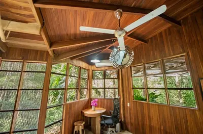 a ceiling fan in a room with windows at Samara Tarantela, Treehouse in Sámara