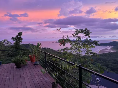 a balcony with a view of the ocean at sunset at Villa with Stunning Isla Tortuga Ocean View, Near Curu Park & Ferry in Blue Zone in Paquera