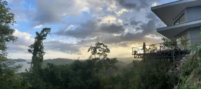a person sitting on a balcony looking out over the mountains at Villa with Stunning Isla Tortuga Ocean View, Near Curu Park & Ferry in Blue Zone in Paquera