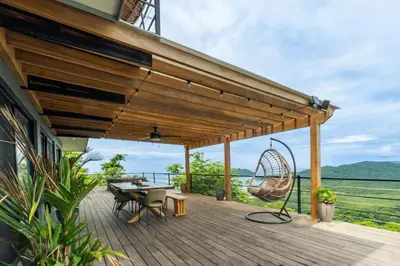 a wooden deck with a table and a swing at Villa with Stunning Isla Tortuga Ocean View, Near Curu Park & Ferry in Blue Zone in Paquera