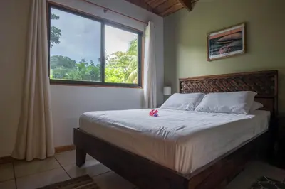 a bedroom with a large bed with a window at Villas Solar in Santa Teresa Beach