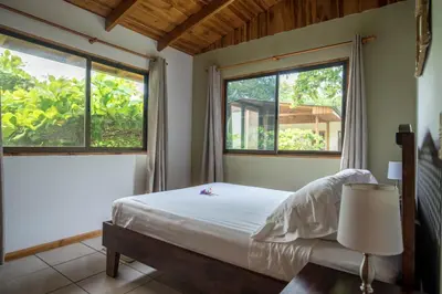 a bedroom with a bed and two windows at Villas Solar in Santa Teresa Beach