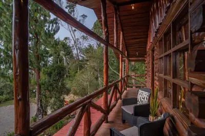 a porch of a cabin with chairs and trees at Cabaña English Evergreen in Jardín