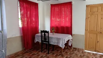 a dining room with red curtains and a table with two chairs at Hospedaje Herradura de Rivas in Rivas