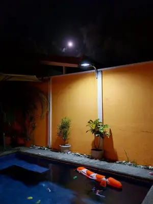 a swimming pool at night next to a yellow wall at An ideal place to share with family and friends in Bejuco