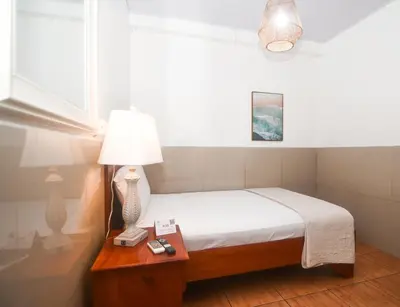 a bedroom with a bed and a table with a lamp at Hotel Aldea Pura Vida in Puntarenas