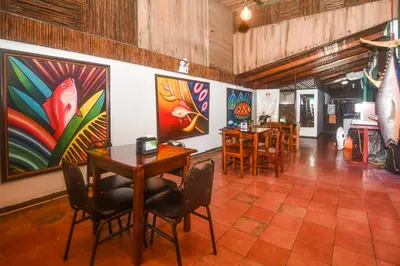 a room with tables and chairs and paintings on the walls at Hotel Aldea Pura Vida in Puntarenas