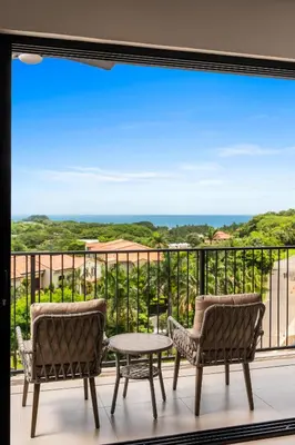 a balcony with two chairs and a table at Costa Elena at Naumi, Ocean Views & Beach Club in Sardinal