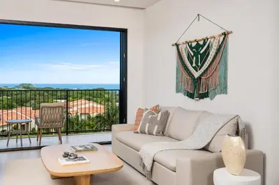 a living room with a couch and a large window at Costa Elena at Naumi, Ocean Views & Beach Club in Sardinal