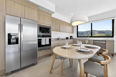 a kitchen with a table and a stainless steel refrigerator at Mar y Selva at Naumi, Ocean Views & Beach Club in Sardinal