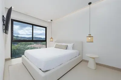 a white bedroom with a large bed and a window at Mar y Selva at Naumi, Ocean Views & Beach Club in Sardinal