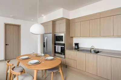 a kitchen with a wooden table and some chairs and a table and a kitchen at Sol Pacífico at Naumi, Ocean Views & Beach Club in Sardinal