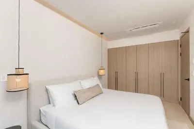 a bedroom with a white bed and a cabinet at Sol Pacífico at Naumi, Ocean Views & Beach Club in Sardinal