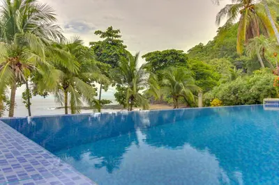 a swimming pool with a view of the ocean and palm trees at Bahia Pez Vela Villa at 18 in Ocotal