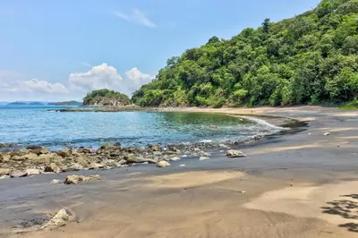 a beach with rocks and the water and trees at Bahia Pez Vela Villa at 18 in Ocotal