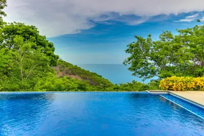 a swimming pool with trees in the background at Bahia Pez Vela Villa at 18 in Ocotal