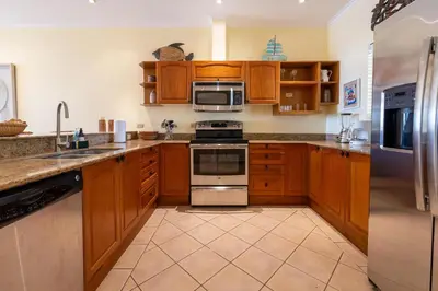 a kitchen with wooden cabinets and stainless steel appliances at Sunrise 7 - 2 Bedroom, Ocean View Condo in Tamarindo