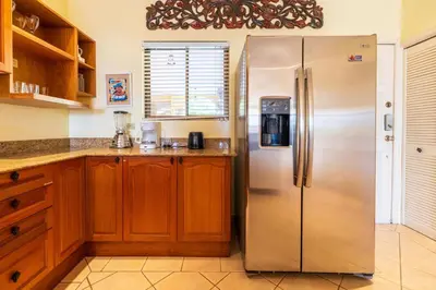 a kitchen with a stainless steel refrigerator and wooden cabinets at Sunrise 7 - 2 Bedroom, Ocean View Condo in Tamarindo