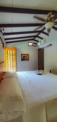 a large white bed in a room with a ceiling fan at La Uvita Perdida in Uvita
