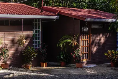 a house with a red roof and a porch with plants at La Uvita Perdida in Uvita
