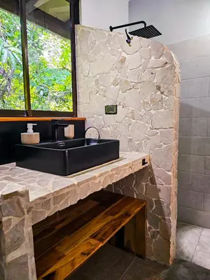 a bathroom with a black sink and a stone wall at La Uvita Perdida in Uvita