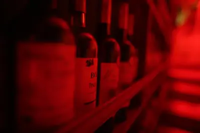 a row of red wine bottles in a wine cellar at La Uvita Perdida in Uvita