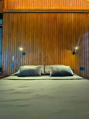 a bed with two pillows in front of a wooden wall at La Uvita Perdida in Uvita
