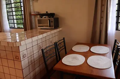 a kitchen with two wooden tables and a microwave at Cabinas Las Chinitas in Zapotal