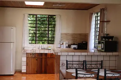 a kitchen with a refrigerator and a counter with chairs at Cabinas Las Chinitas in Zapotal