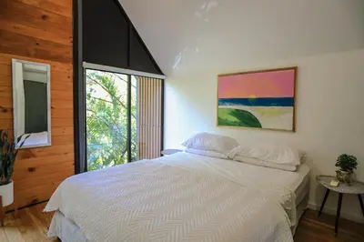 a bedroom with a white bed and a large window at D'Village 8 - 1 bdr loft in Mal País in Mal País