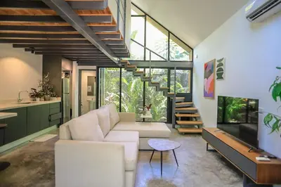 a living room with a white couch and a staircase at D'Village 8 - 1 bdr loft in Mal País in Mal País