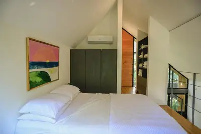 a bedroom with a large white bed with a painting on the wall at D'Village 8 - 1 bdr loft in Mal País in Mal País