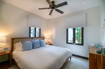 a bedroom with a bed with blue pillows and a ceiling fan at Casa Ronda 18 -Las Catalinas in Playa Danta
