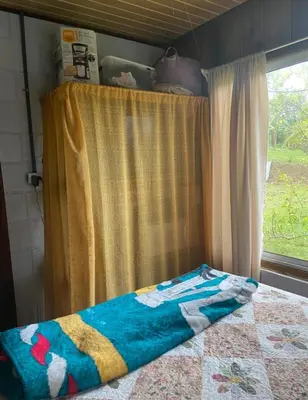 a bed with a quilt on it in front of a window at Quinta de Montaña, San Carlos in Vara Blanca