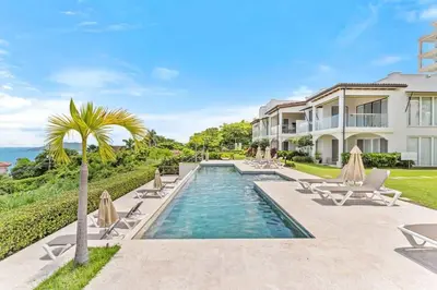 a villa with a swimming pool and chairs and a house at Luxury Oceanview Condo with Pool in Tamarindo