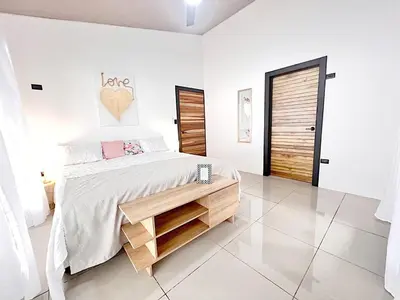 a white bedroom with a large bed with a wooden drawer at Fruit Villa Uvita in Uvita