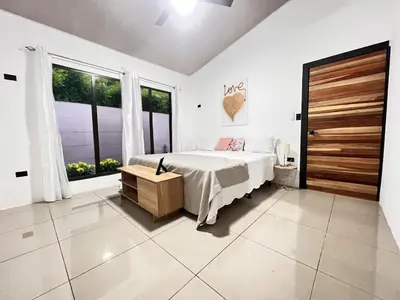 a white bedroom with a bed and a large window at Fruit Villa Uvita in Uvita