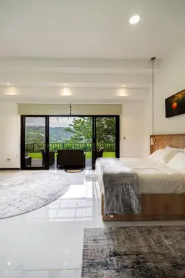 a bedroom with a large bed and a living room at La Danta Lodge - Celeste River in Bijagua