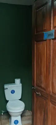 a bathroom with a toilet and a wooden door at Casa Perezosa in Parrita