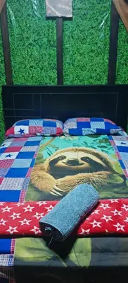 a bed with a blanket and pillows on it at Casa Perezosa in Parrita
