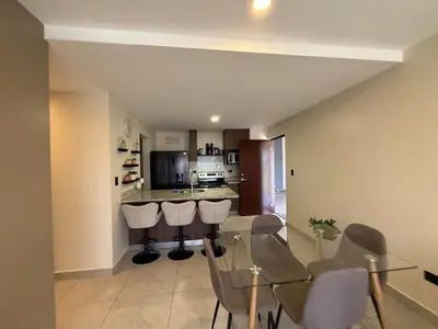a dining room and kitchen with a glass table and chairs at Tropical Sunshine in Alajuela City