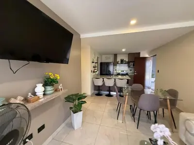 a living room with a table and a television on a wall at Tropical Sunshine in Alajuela City