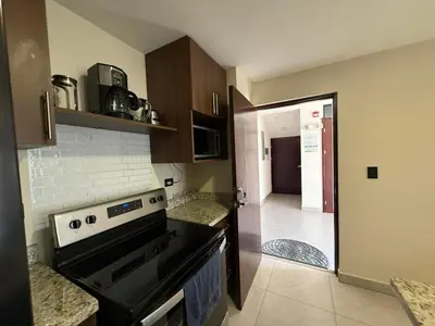 a kitchen with a stove and a door to a hallway at Tropical Sunshine in Alajuela City