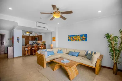 a living room with a couch and a ceiling fan at Beachfront view large Condo with Pools PVT luxury patio in great location in Jacó